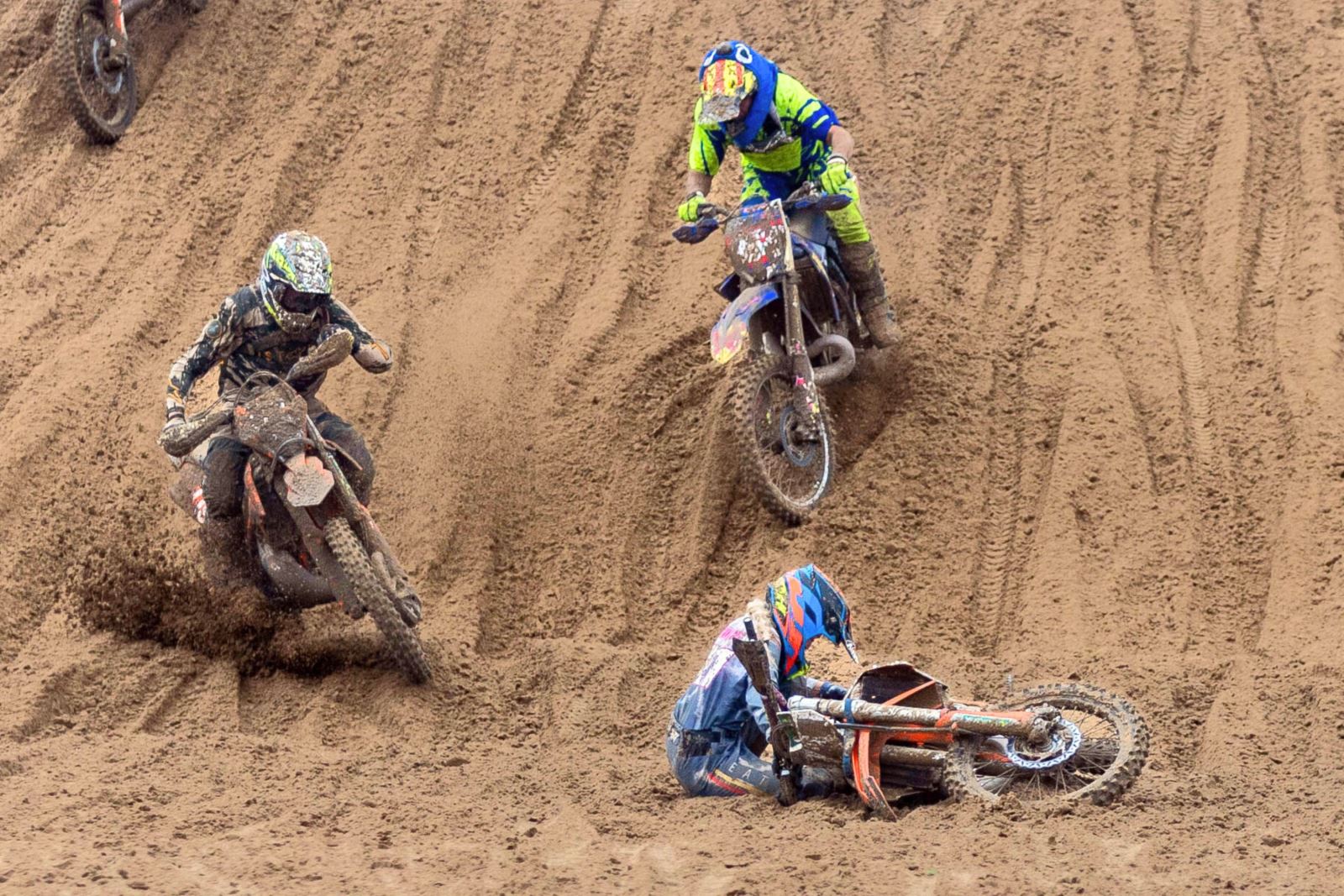 Two riders in the Weston-super-Mare Beach Race navigate their way around a fallen rider at the b ottom of a sand dune
